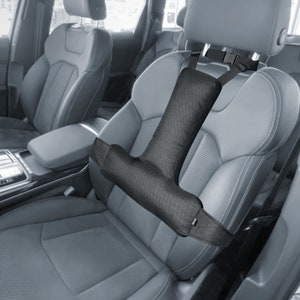 May include: A black car seat headrest support with a padded armrest and adjustable straps. The support is designed to provide comfort and support for the head and neck while driving.