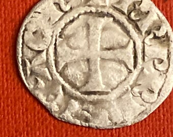 May include: A silver coin with a cross in the center surrounded by a circular design. The coin is worn and has a patina.