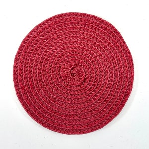 Peut inclure: Un set de table rond en osier rouge avec un motif circulaire. Le set de table est fait d'un matériau naturel et a un aspect rustique.