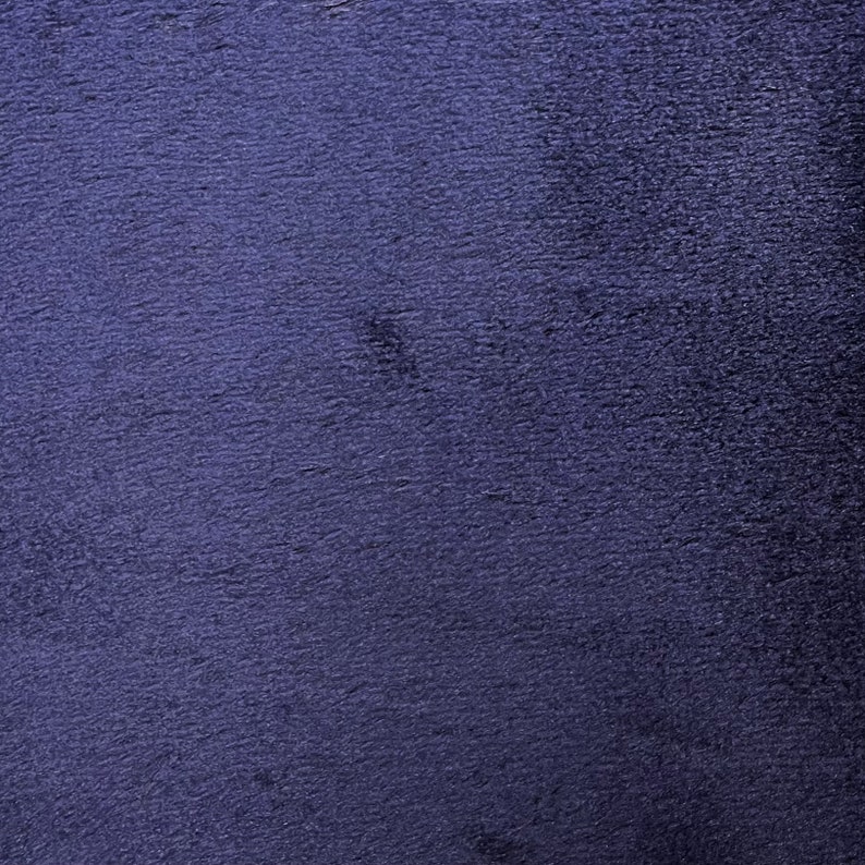 May include: A close-up of a dark blue textured fabric. The fabric has a slightly fuzzy surface.