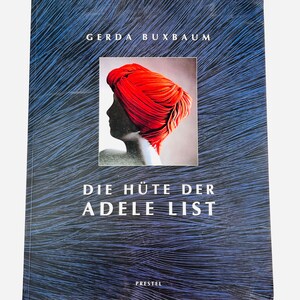 May include: A book cover with a blue background and the text "GERDA BUXBAUM" at the top. The cover features a central image of a person wearing a red turban. The title "DIE HÜTE DER ADELE LIST" is below the image, with "PRESTEL" at the bottom.