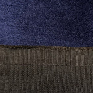 May include: Close-up of a dark blue fabric with a soft, fuzzy texture. The fabric is sewn to a black fabric with a woven texture.