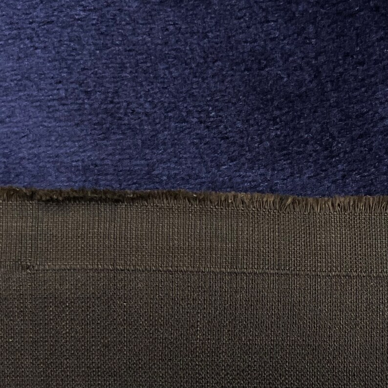 May include: Close-up of a dark blue fabric with a soft, fuzzy texture. The fabric is sewn to a black fabric with a woven texture.