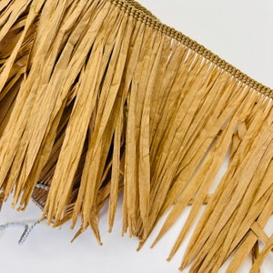 May include: Brown paper fringe trim with a woven edge. The fringe is made of thin strips of paper that are frayed at the ends.