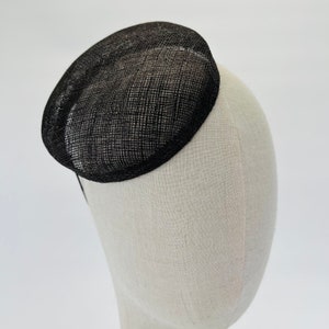 May include: A black, round, woven hat with a wide brim. The hat is made of a fine, delicate material and has a slightly textured surface.
