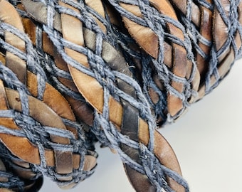 Puede incluir: Primer plano de un cordón trenzado de cuero marrón y algodón azul. El cordón está tejido en un patrón complejo, creando un diseño texturizado y visualmente atractivo.