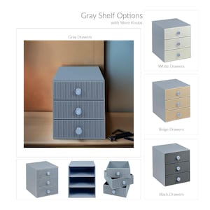May include: Gray shelf options with silver knobs. The image shows a gray three-drawer storage unit with silver knobs. Additional options include white, beige, and black drawers. The text "Gray Shelf Options" is at the top of the image.