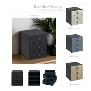 May include: A black three-drawer storage unit with black satin sheen knobs. The unit has a ribbed design on the drawer fronts. Additional options include white, gray, and beige drawer fronts. The text "Black Shelf Options" is at the top.