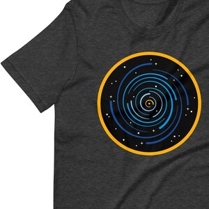 May include: Dark gray t-shirt with a circular design of a blue and white spiral galaxy with a yellow outer ring.