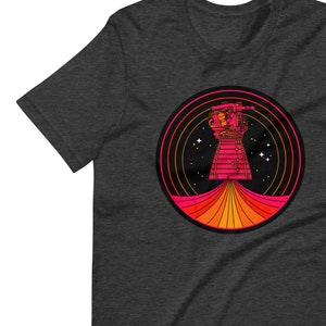 May include: A dark heather grey V-neck t-shirt with a retro-style graphic of a pink and orange spaceship in a circle with a black background and stars.