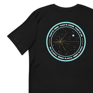 Puede incluir: Camiseta negra con un gráfico circular azul y dorado que presenta una imagen estilizada de la nave espacial Voyager 1 y el texto "That's here. That's home. That's us."