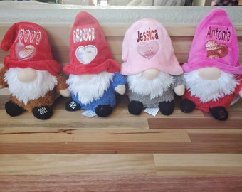 May include: Four plush gnomes with red, pink, and gray hats. Each gnome has a heart with a name on it: Brandon, Jessica, Antonia, and a fourth gnome with a heart that says "Love".