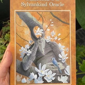 May include: Guidebook to the Sylvankind Oracle by Greg White. The cover features a painting of a tree with a face, white flowers, and a bluebird in a nest.