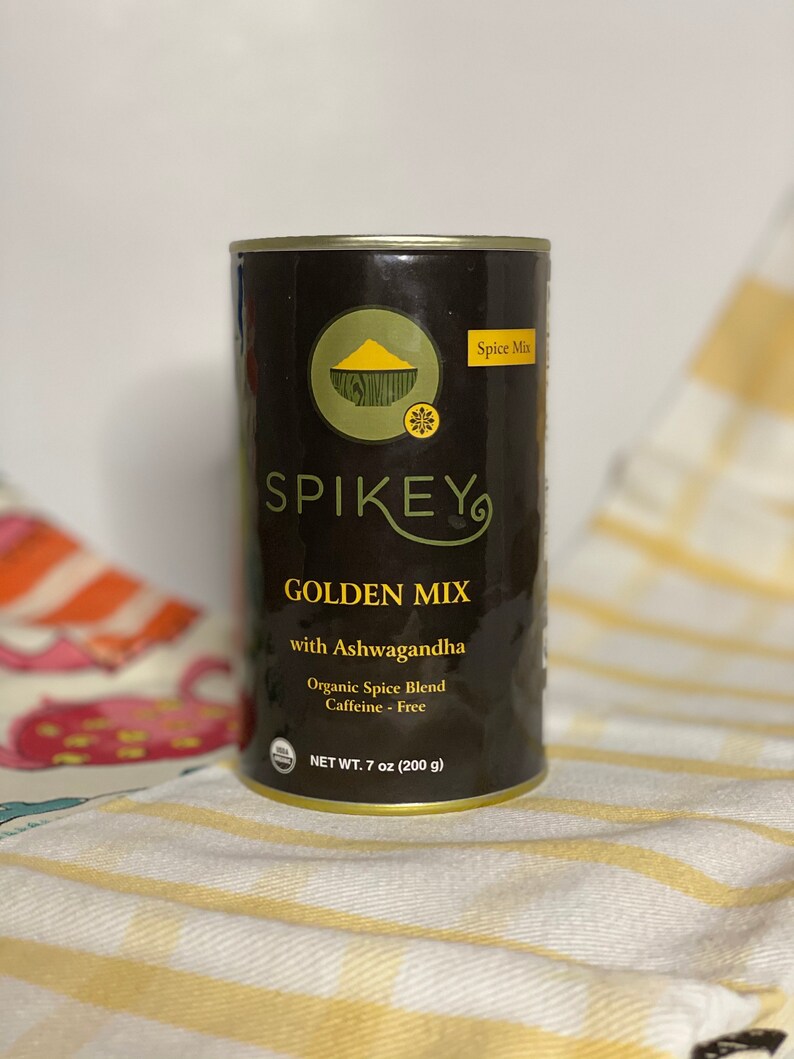 K&ouml;nnte beinhalten: Eine schwarze und goldene Dose SPIKEY GOLDEN MIX mit Ashwagandha, einem Bio-Gew&uuml;rz-Mix. Die Dose enth&auml;lt 200 Gramm (7 Unzen) und ist koffeinfrei.