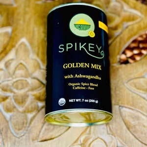 K&ouml;nnte beinhalten: Eine schwarze Dose mit goldenem Deckel und einem wei&szlig;en Etikett. Das Etikett lautet "SPIKEY GOLDEN MIX with Ashwagandha Organic Spice Blend Caffeine - Free NET WT. 7 oz (200 g)". Auf der Dose befindet sich ein USDA-Bio-Siegel.