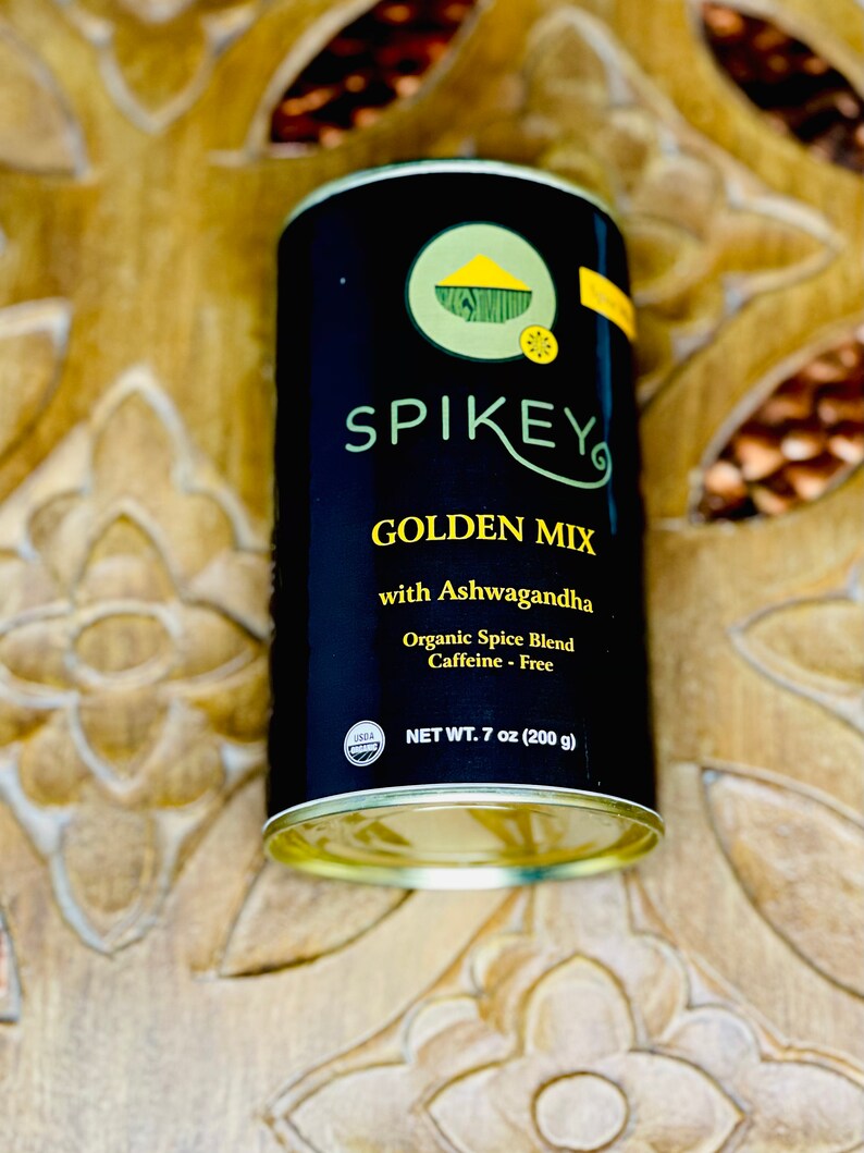 K&ouml;nnte beinhalten: Eine schwarze Dose mit goldenem Deckel und einem wei&szlig;en Etikett. Das Etikett lautet "SPIKEY GOLDEN MIX with Ashwagandha Organic Spice Blend Caffeine - Free NET WT. 7 oz (200 g)". Auf der Dose befindet sich ein USDA-Bio-Siegel.