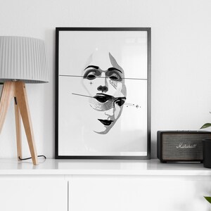 May include: A white shelf with a black framed print of a black and white illustration of a face. A gray lamp with a wooden tripod base is on the left side of the shelf. A black speaker with the word "Marshall" on it is on the right side of the shelf. A green plant is on the right side of the shelf.