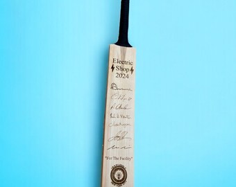 May include: A wooden cricket bat with a black handle and signatures on the surface. The bat is engraved with the text "Electric Shop 2024" and "For The Facility".