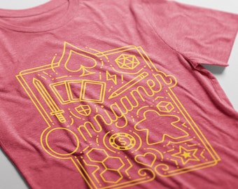 Puede incluir: Una camiseta roja con un diseño gráfico amarillo que presenta la palabra "Omjigamer" rodeada de varios iconos relacionados con los juegos, incluidos dados, cartas, un peón y una estrella.