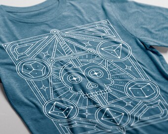 May include: A blue t-shirt with a white graphic design of a skull with a sword through it, surrounded by dice and geometric shapes.