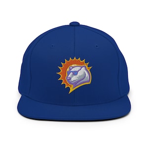 May include: A royal blue baseball cap with a white polar bear wearing sunglasses in front of an orange sun. The bear and sun are embroidered on the front of the cap.