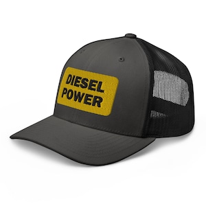 May include: A dark grey trucker hat with a black mesh back. The hat has a yellow patch with the text "DIESEL POWER" in black.