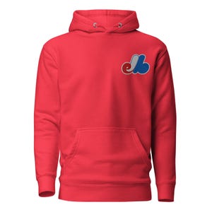 May include: Red hooded sweatshirt with a blue and white embroidered logo on the left chest. The logo is a stylised "M" with a cloud shape.