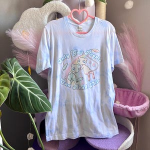 Pastel blue and white tie dye t-shirt with one mew and one shiny mew in front of a rainbow. The text on the shirt reads Only Gay People Can Read This.