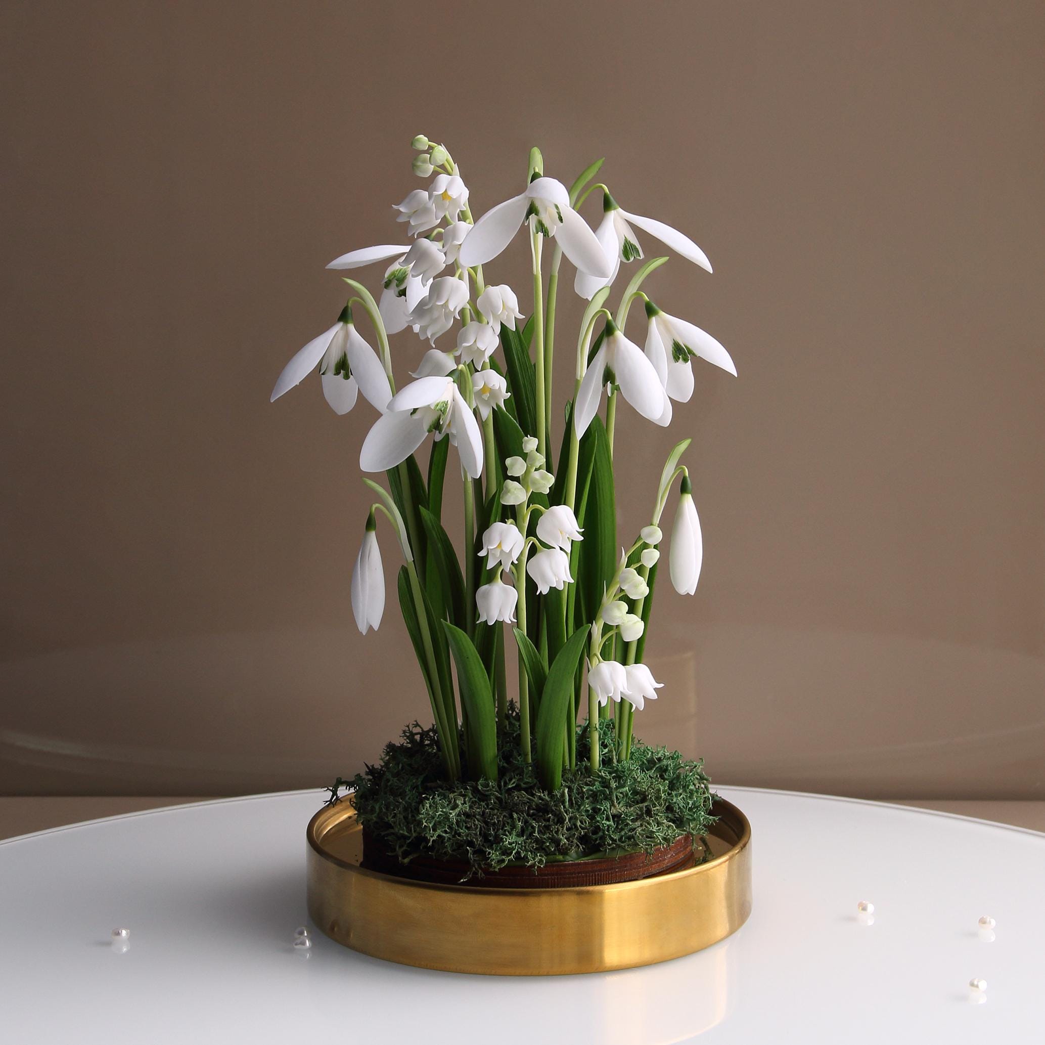 ガラスドームに入った磁器のスノードロップとスズラン：花のセンター