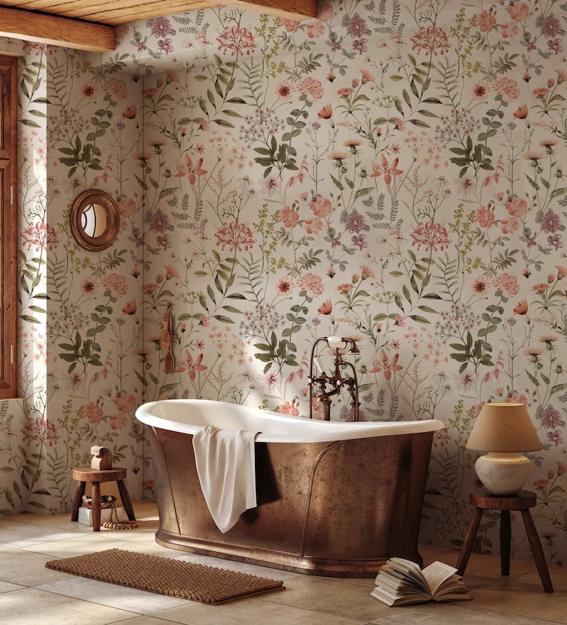 May include: A copper bathtub with a white towel inside sits in a bathroom with a floral wallpaper. The wallpaper features a variety of pink, green, and white flowers. A small wooden stool with a lamp sits in the corner of the room.
