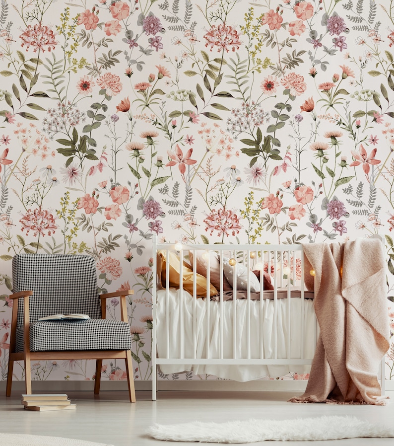 May include: A white crib with a pink and white floral wallpaper background. The crib has a white mattress and a pink blanket. There is a white chair with a black and white checkered pattern in the foreground.