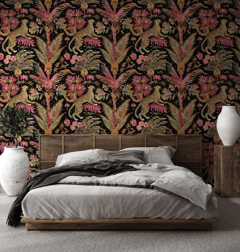 May include: A bedroom featuring wallpaper with a black background and a repeating pattern of gold leopards, pink palm leaves, and tropical flowers. The bed has a wooden frame, a cane headboard, and gray bedding. Two large white vases sit on either side.