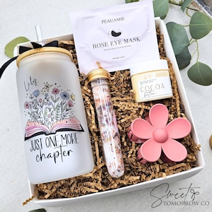 May include: A gift box containing a frosted glass tumbler with a bamboo lid, a clear straw, and the text 'Lily' and 'JUST ONE MORE CHAPTER' with a floral book graphic. Includes a Peauamie rose eye mask, cocoa butter, a floral bath salt tube, and a pink flower hair clip.