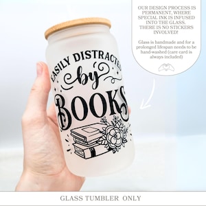 a hand holding a glass tumbler with a book on it