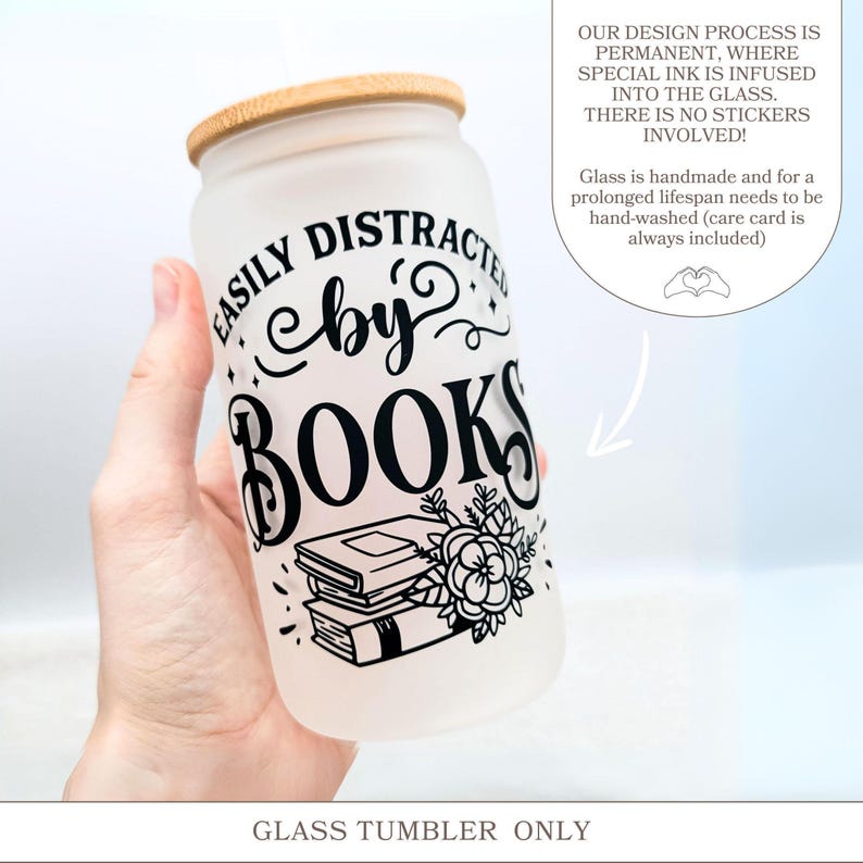 a hand holding a glass tumbler with a book on it