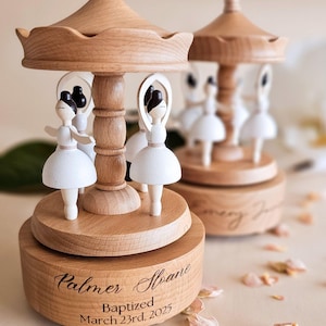 two wooden carousel-like objects with white figures on them, placed on a table with scattered flower petals around them.