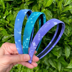 May include: Three fabric headbands with a white star pattern on a blue, teal, and purple background.