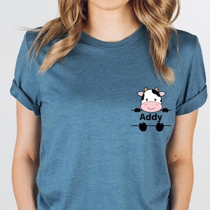 May include: A blue t-shirt with a cartoon cow peeking over a sign that says "Addy".