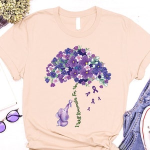 May include: A heather peach t-shirt with a purple flower bouquet and a small elephant holding a purple ribbon. The text "I Will Remember For You" is written on the shirt.