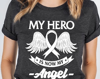 May include: Dark heather grey t-shirt with the text "MY HERO IS NOW MY ANGEL" and "LUNG CANCER AWARENESS" in white. The design includes angel wings and a ribbon.