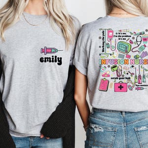 May include: A light grey t-shirt with a syringe graphic and the name "emily" in black. The back of the shirt features a colourful design with medical equipment and the words "INFUSION NURSE". The design includes the text "Working the pole", "scrub your hub", and "Size matters".