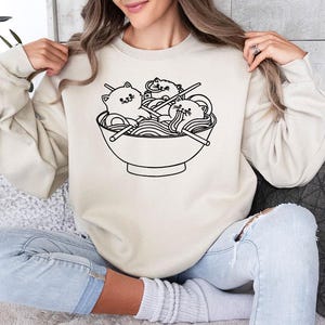 a woman sitting on a couch holding up a sweatshirt