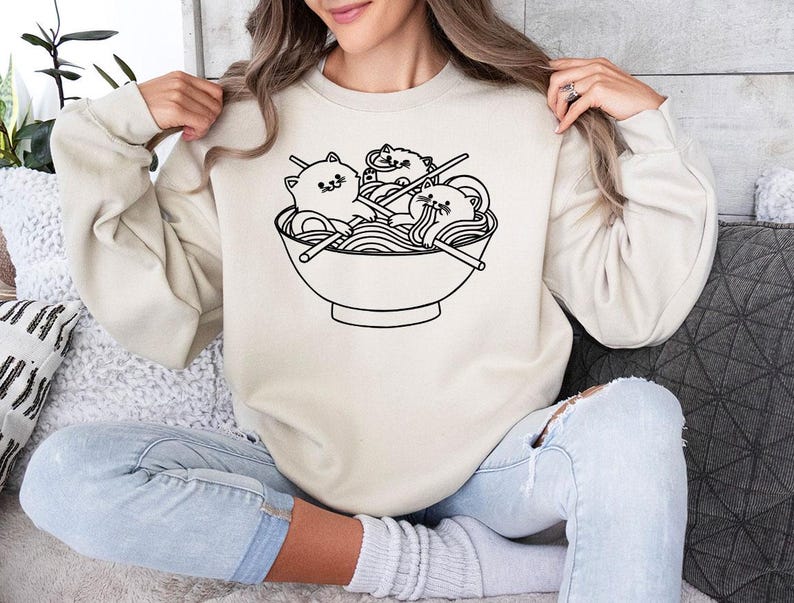 a woman sitting on a couch holding up a sweatshirt