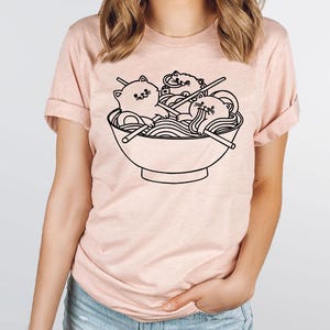 a woman wearing a t - shirt with a picture of a bowl of noodles