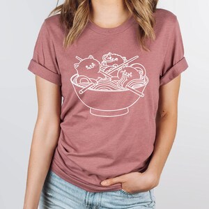 a woman wearing a t - shirt with a picture of a bowl of noodles