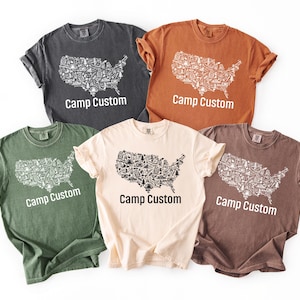 a collection of six t-shirts, each with a unique design and color, all featuring the text "Camp Custom" prominently displayed.