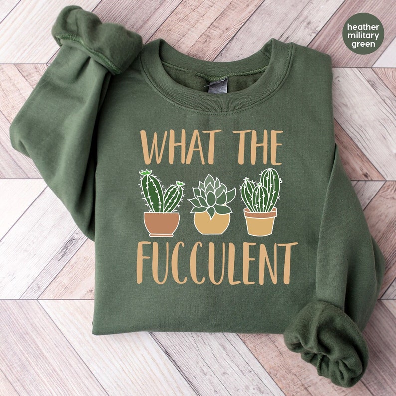 May include: A green sweatshirt with the text "WHAT THE FUCCULENT" in orange. Three cartoon succulents are pictured below the text.