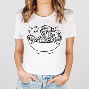 a woman wearing a t - shirt with a picture of a bowl of noodles