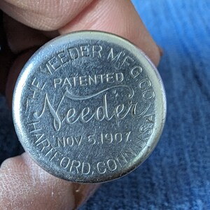 May include: Close-up of a silver metal bottle cap with the text "The Needer Mfg. Co. Patented Nov. 5, 1907, Hartford, Conn. USA" engraved on it.