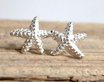 May include: A pair of silver starfish stud earrings. The starfish are textured and have a 3D design.